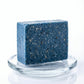 You will be generating high-quality product photos for an online stores product page. The product images should closely match the original products.
      Here is the prompt (IMPORTANT!): """Generate a dynamic commercial shot of the Blueberry Scrub Soap ag