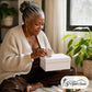 Hearth Nurturer Sanctuary Ritual Box: a woman with silver locs opening her white G Spot Studio ritual box at home